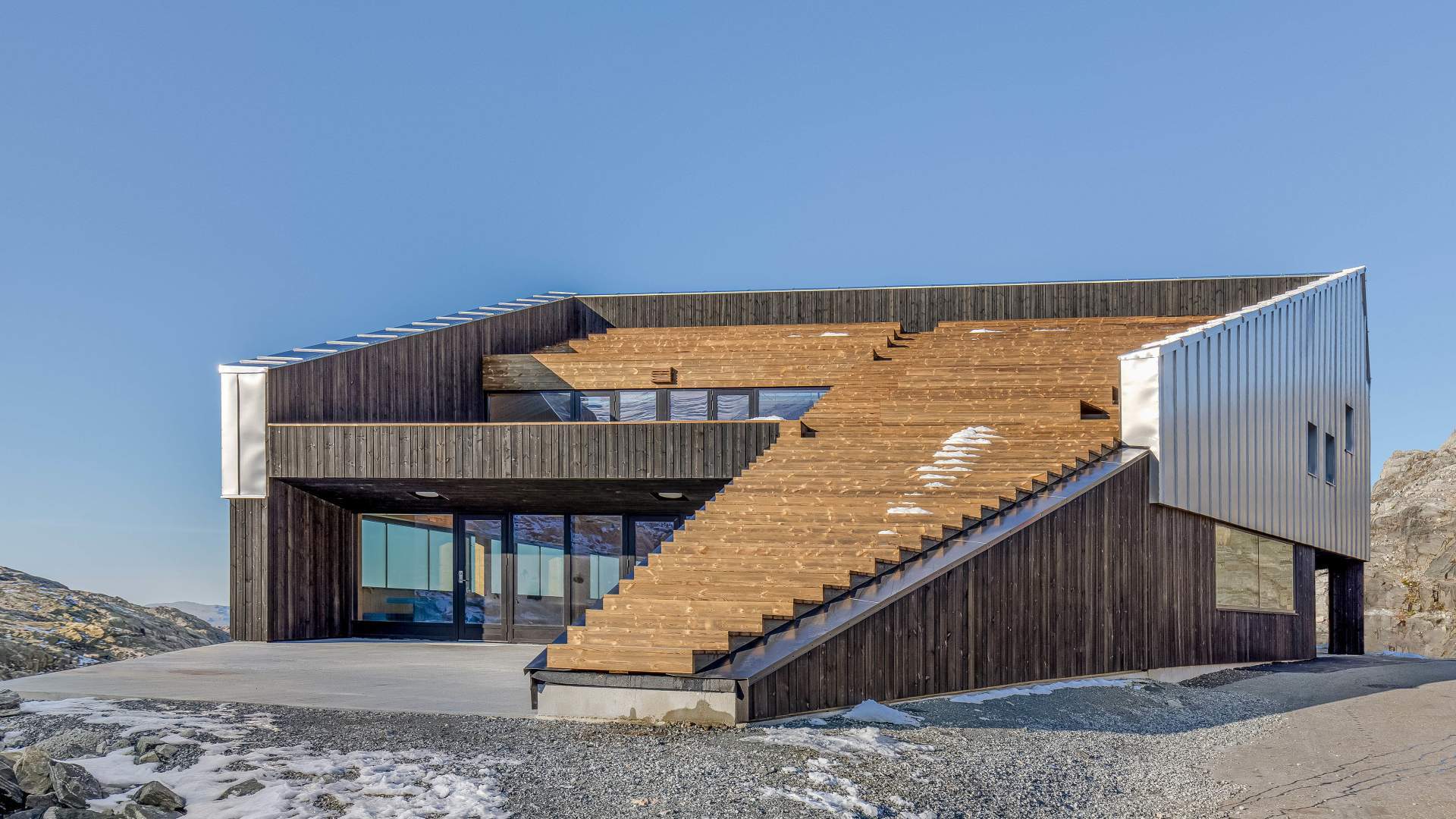 Modern building with dark wood, metal accents, and a large wooden staircase integrated into its facade.