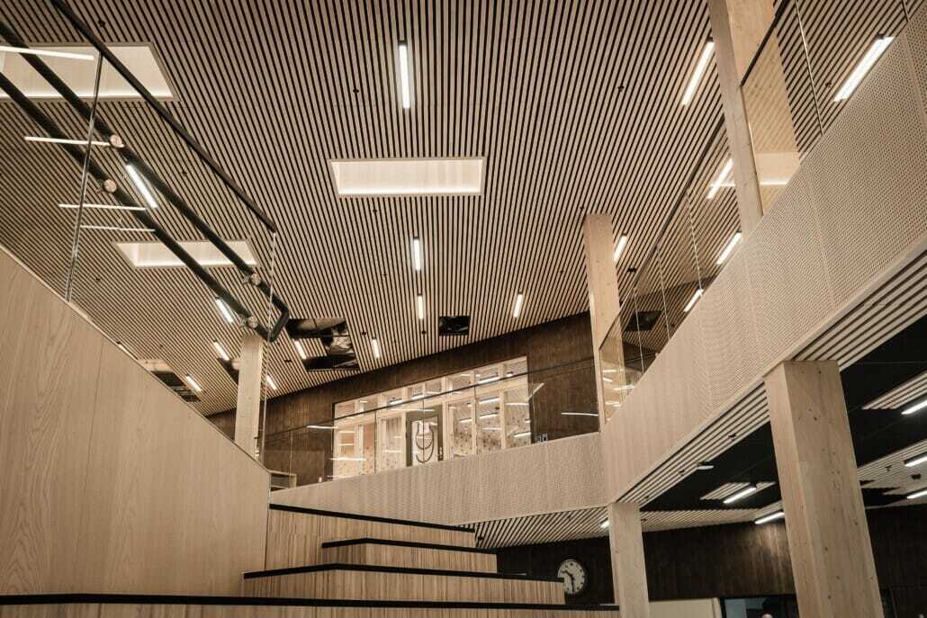 Modern interior: slatted wood ceiling, multi-level design with stairs, and glass railings.