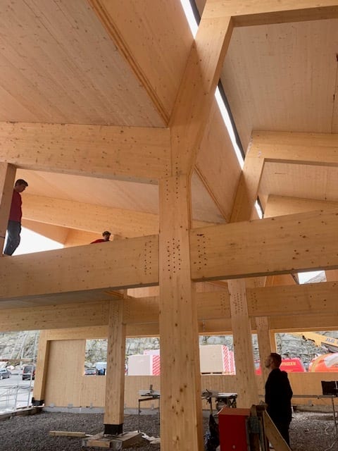 Large wooden building under construction, with exposed beams and columns.
