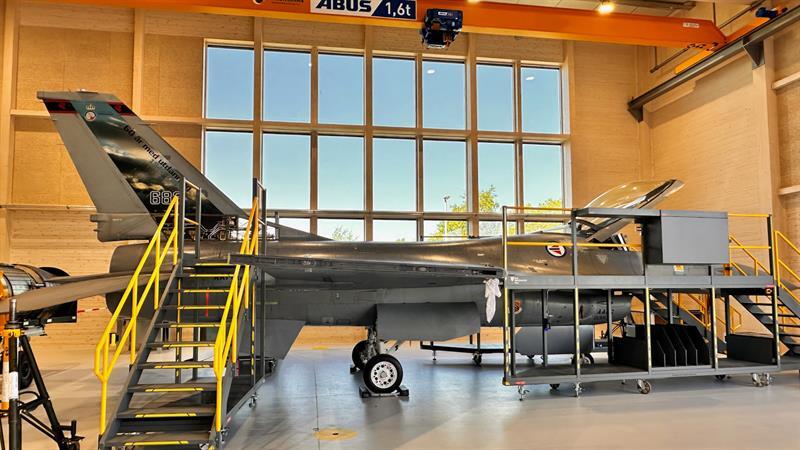 F-16 fighter jet undergoing maintenance in a hangar.