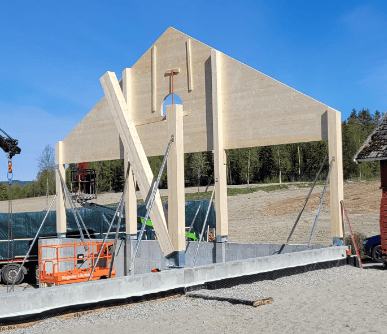 Wooden A-frame building under construction with concrete foundation.
