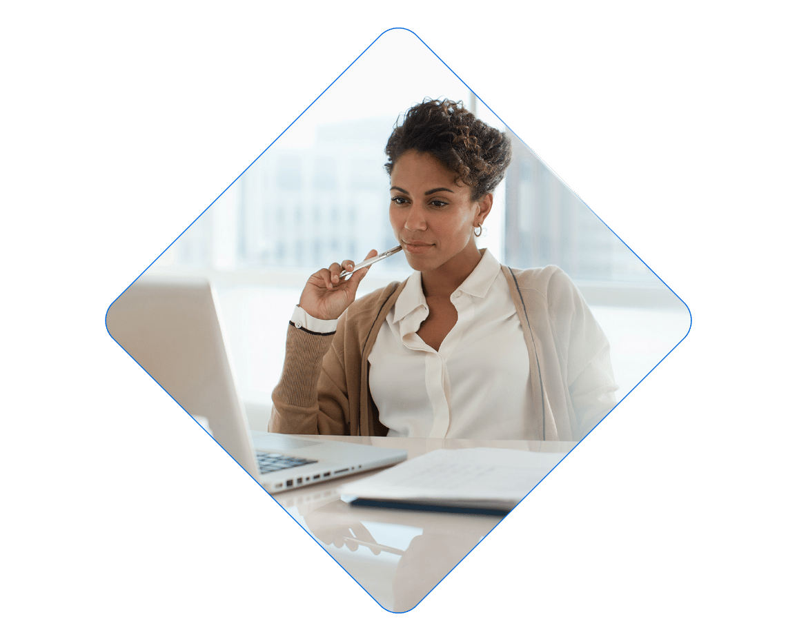 Professional woman focused on her laptop, pen to chin.