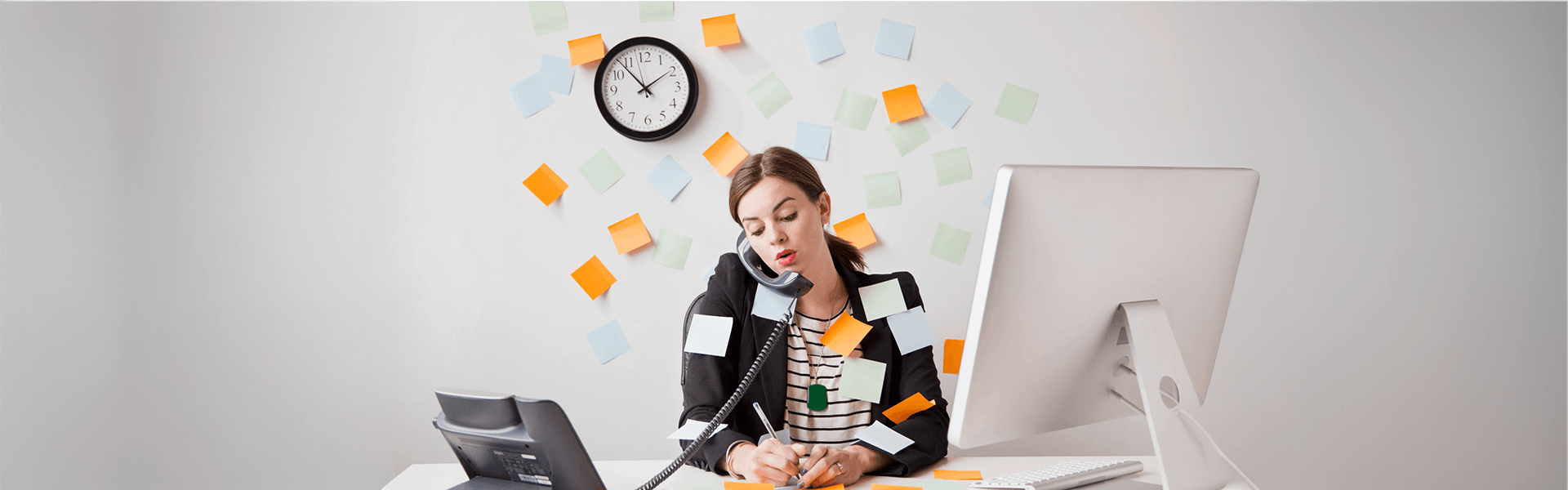Busy woman multitasking on phone, writing, surrounded by sticky notes, with a clock and computer.