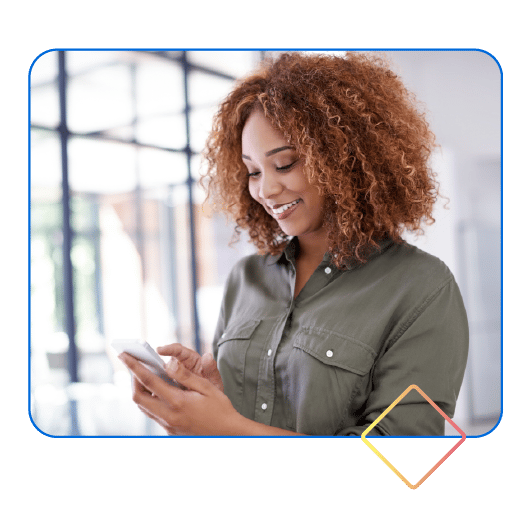 Smiling woman with curly hair looking at her phone, smiling.