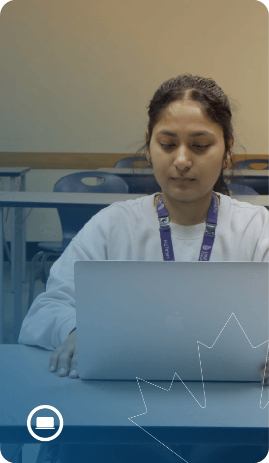 Person sitting front of a laptop in a classroom setting.
