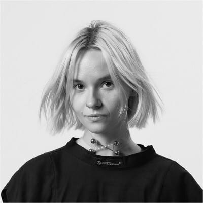 Black and white portrait of a woman with short light hair and a distinctive metallic choker.