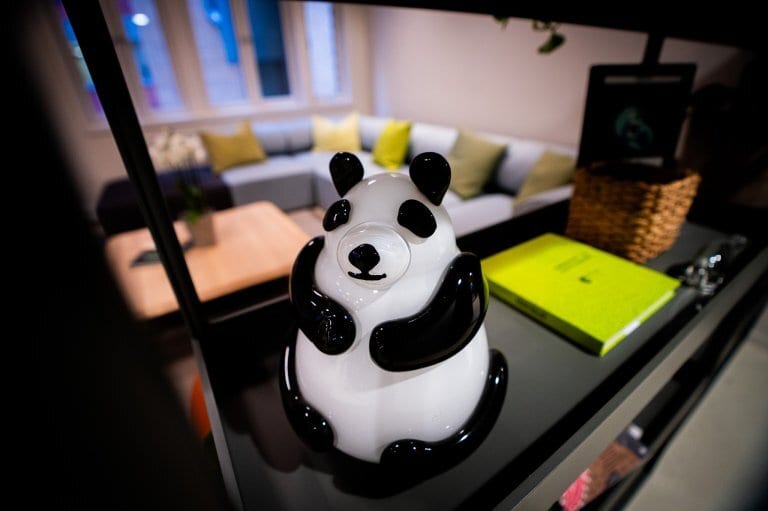Black and white panda figurine on a shelf, blurred living room in background.