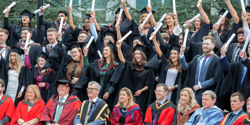 Facial expression, Academic dress, Clothing, Smile, Outerwear, Mortarboard, Scholar, Crowd, Gesture, Graduation