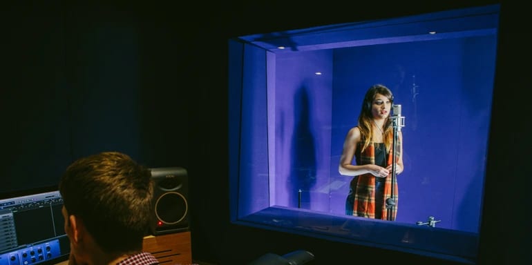 Engineer at console, singer in vocal booth.