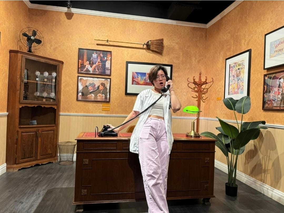 A person talking on an old-fashioned phone in a vintage-style office.