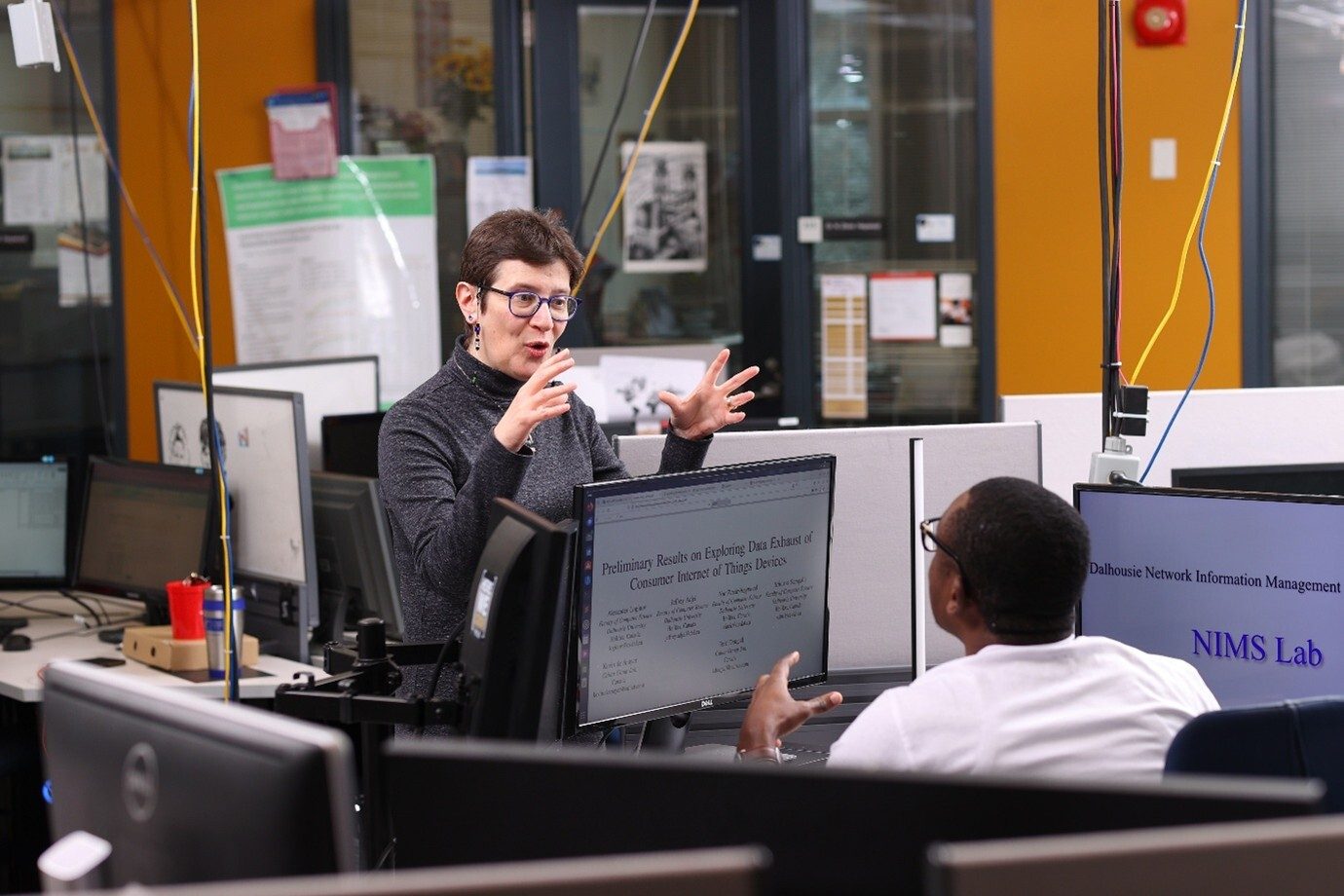 A researcher presents IoT data findings to a colleague in NIMS Lab.