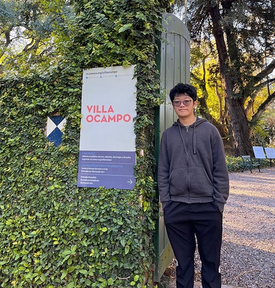 Man next to an ivy-covered sign for "VILLA OCAMPO".