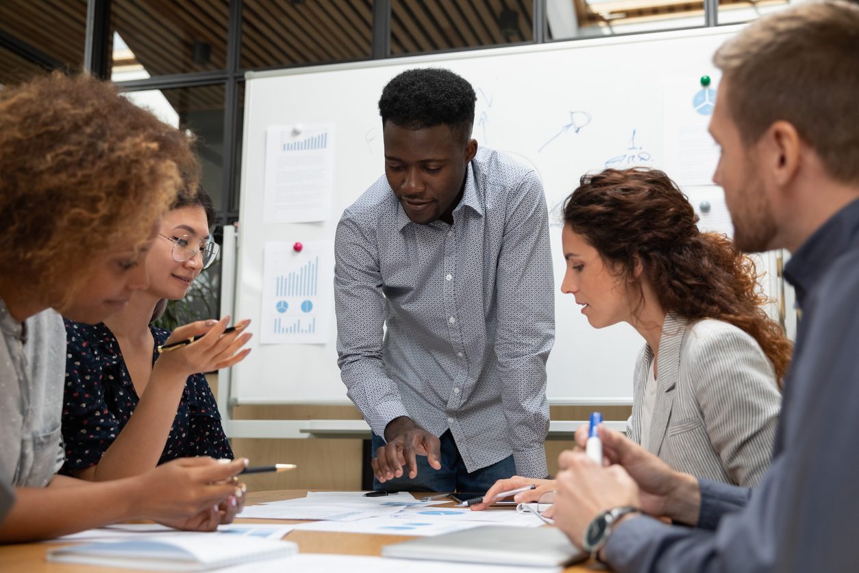 Diverse team in a business meeting, a Black man pointing at documents.