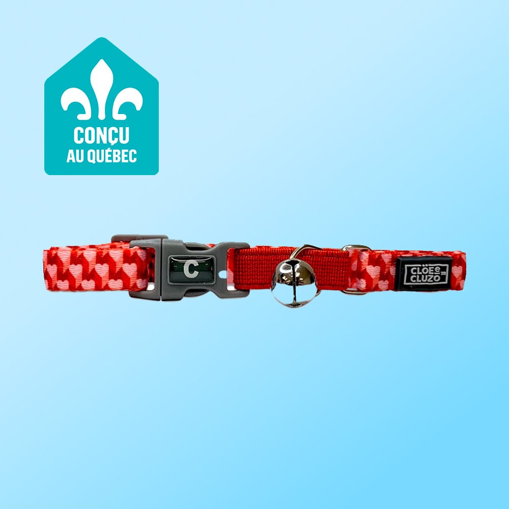 Red heart-patterned cat collar with bell, 'C' buckle, and 'CLOÉ & CLUZO' tag. Quebec designed.
