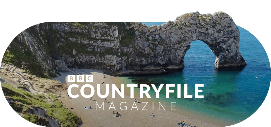 Durdle Door rock arch over a beach and turquoise sea, with BBC Countryfile Magazine text.
