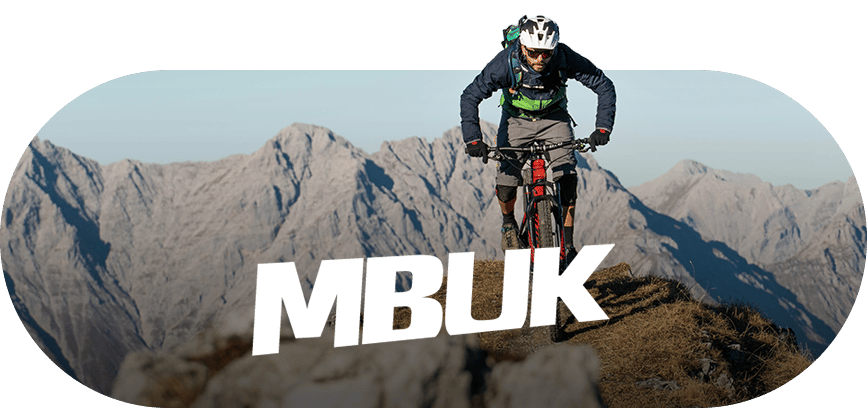 Mountain biker on a mountain ridge with "MBUK" text overlay.