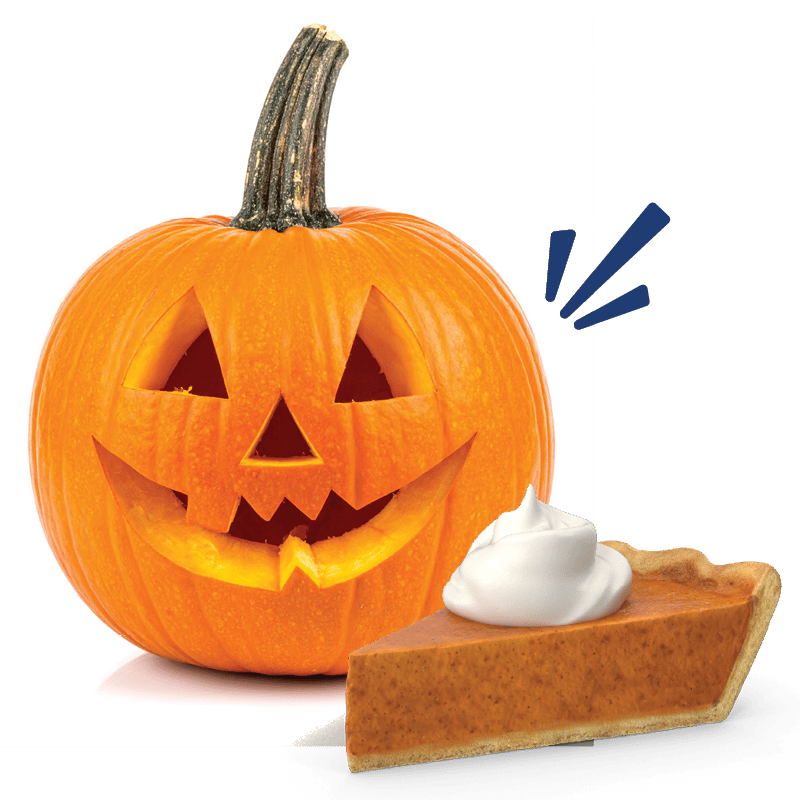 A carved Halloween pumpkin (jack-o'-lantern) next to a slice of pumpkin pie topped with whipped cream.