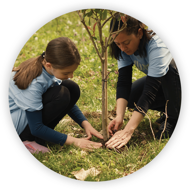 A woman and young girl planting a small tree