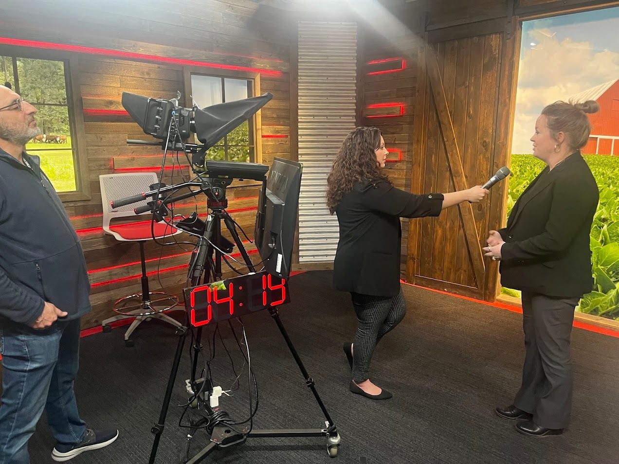 Two women interview in a studio setting, with a camera and man operating equipment.