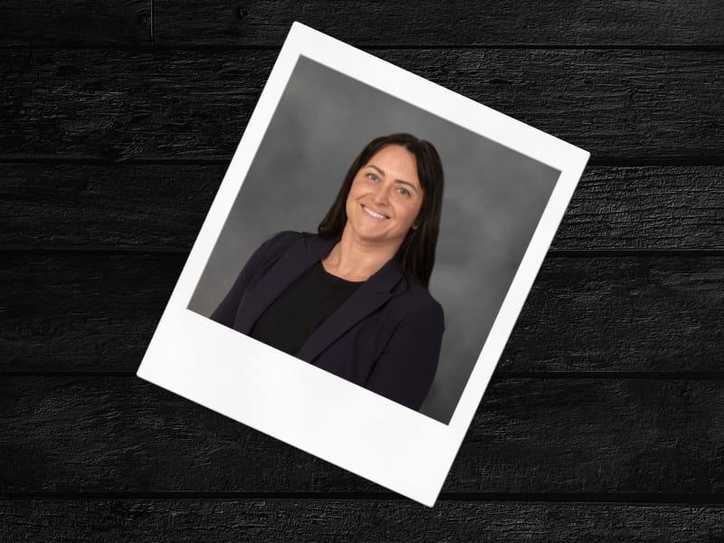 Smiling woman's photo in polaroid on dark wood.