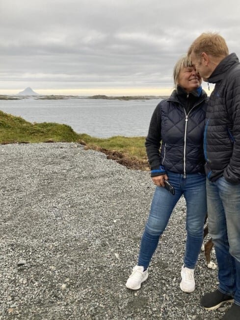 Couple looking at each other by water with islands in distance.
