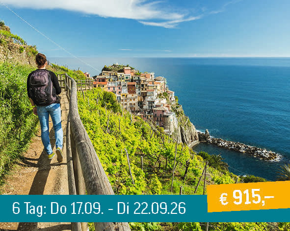 Hiker on a scenic coastal path overlooking a colorful village nestled on cliffs by the blue sea.