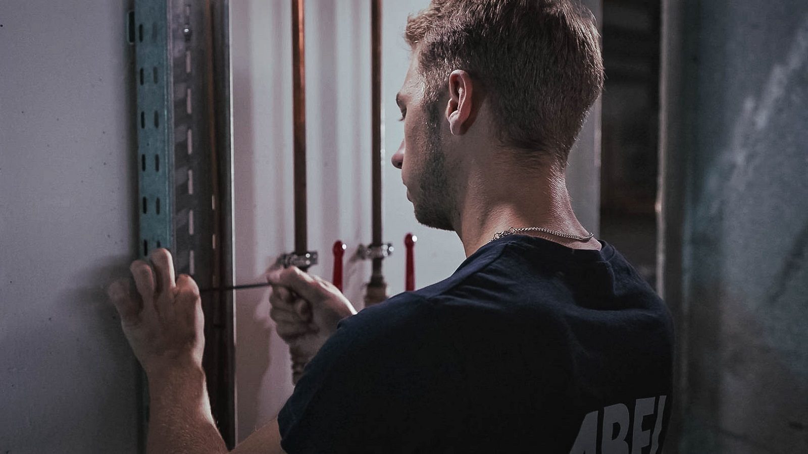 Man adjusting copper pipes with a tool.