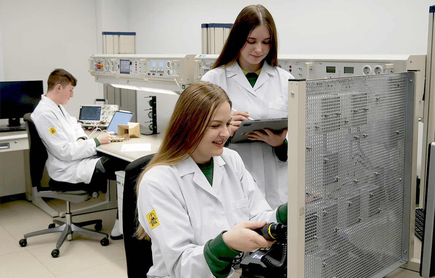 Three students in lab coats collaborating in a modern lab.