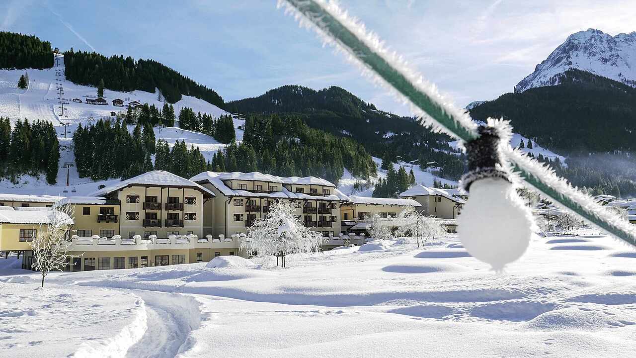 A snowy mountain landscape with a resort, ski lift, and a frosted light bulb in the foreground.