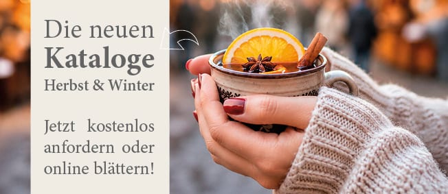 Hands holding a steaming mug of spiced drink with orange and cinnamon, promoting new Autumn & Winter catalogs.
