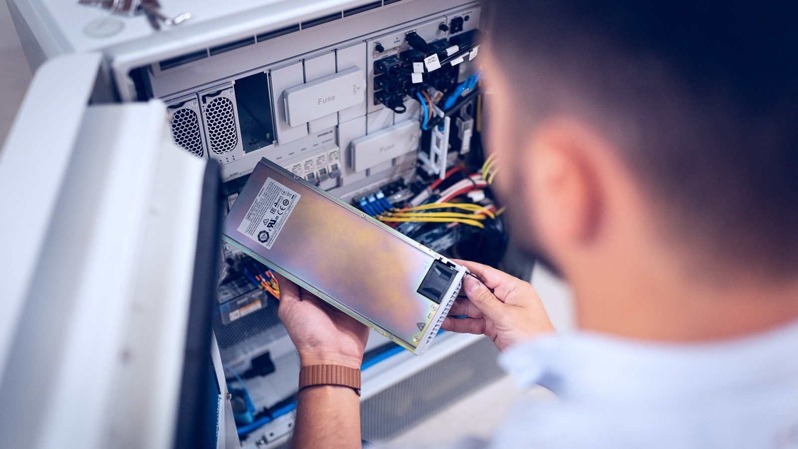 Person installing power supply unit into electronic equipment.