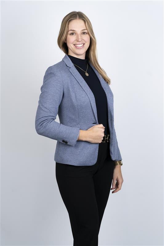 Smiling woman in a blue blazer, black top, and black pants.