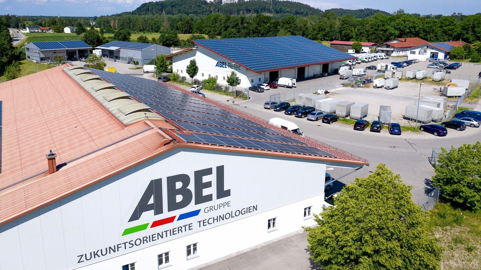 Aerial view of an industrial complex with solar panels on multiple roofs and the "ABEL GRUPPE" logo.
