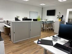 Modern office space with desks, computers, and a communal high-top table.