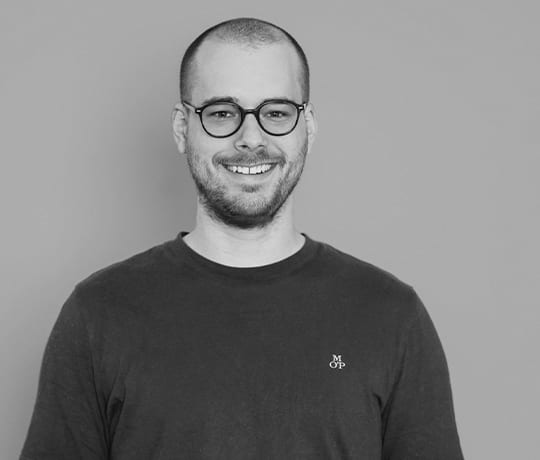 Black and white portrait of a smiling man with glasses and a beard.