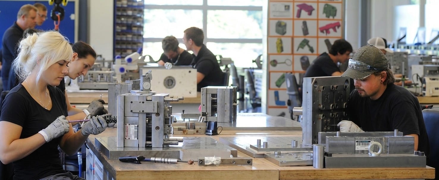 Workers assembling metal molds and components in a workshop.
