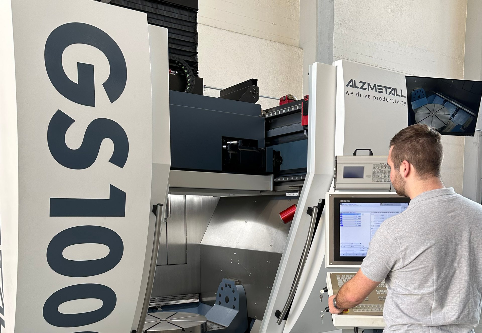 Man operating an ALZMETALL GS 100 CNC machine from its control panel.