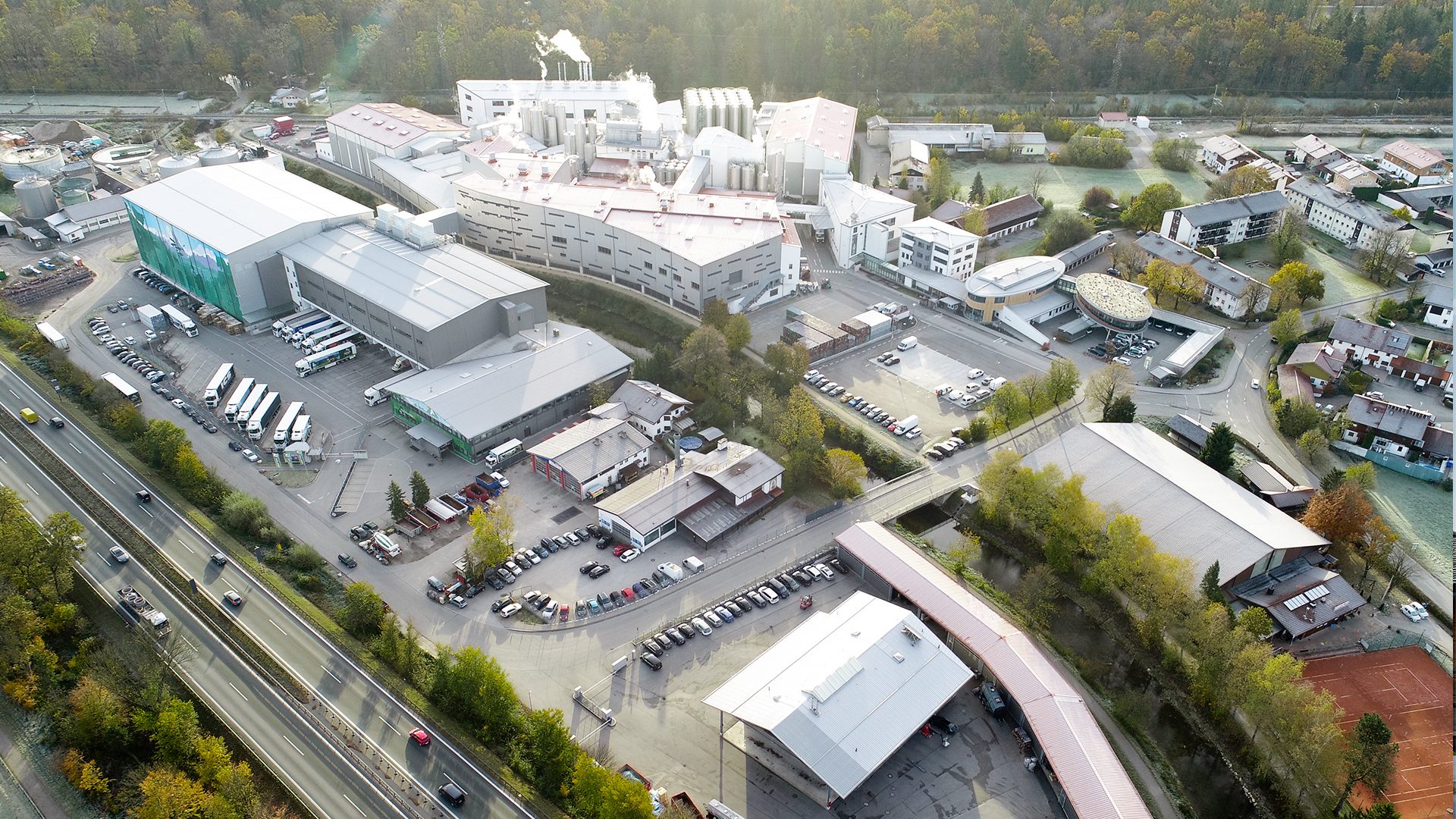 Aerial view of a factory, highway, residential homes, and a river.