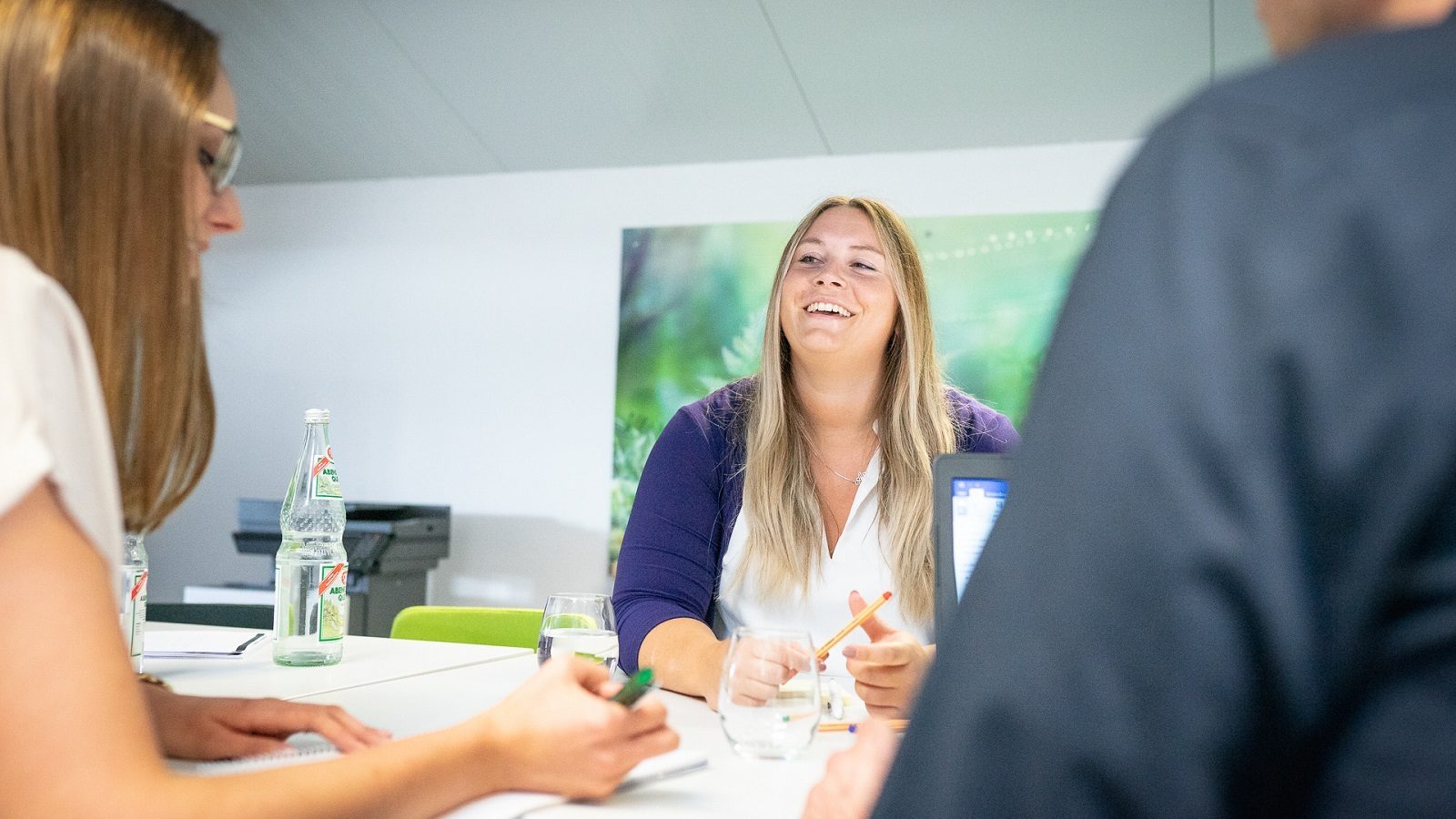 Happy blonde woman laughing during a meeting with colleagues.