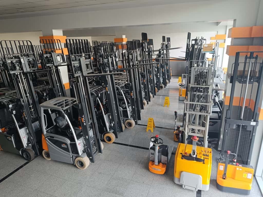 New forklifts, reach trucks, and electric pallet jacks displayed in a showroom.