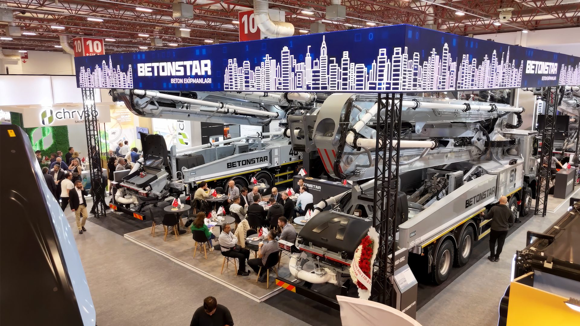 Betonstar concrete pump trucks displayed at a trade show, with people gathered around.