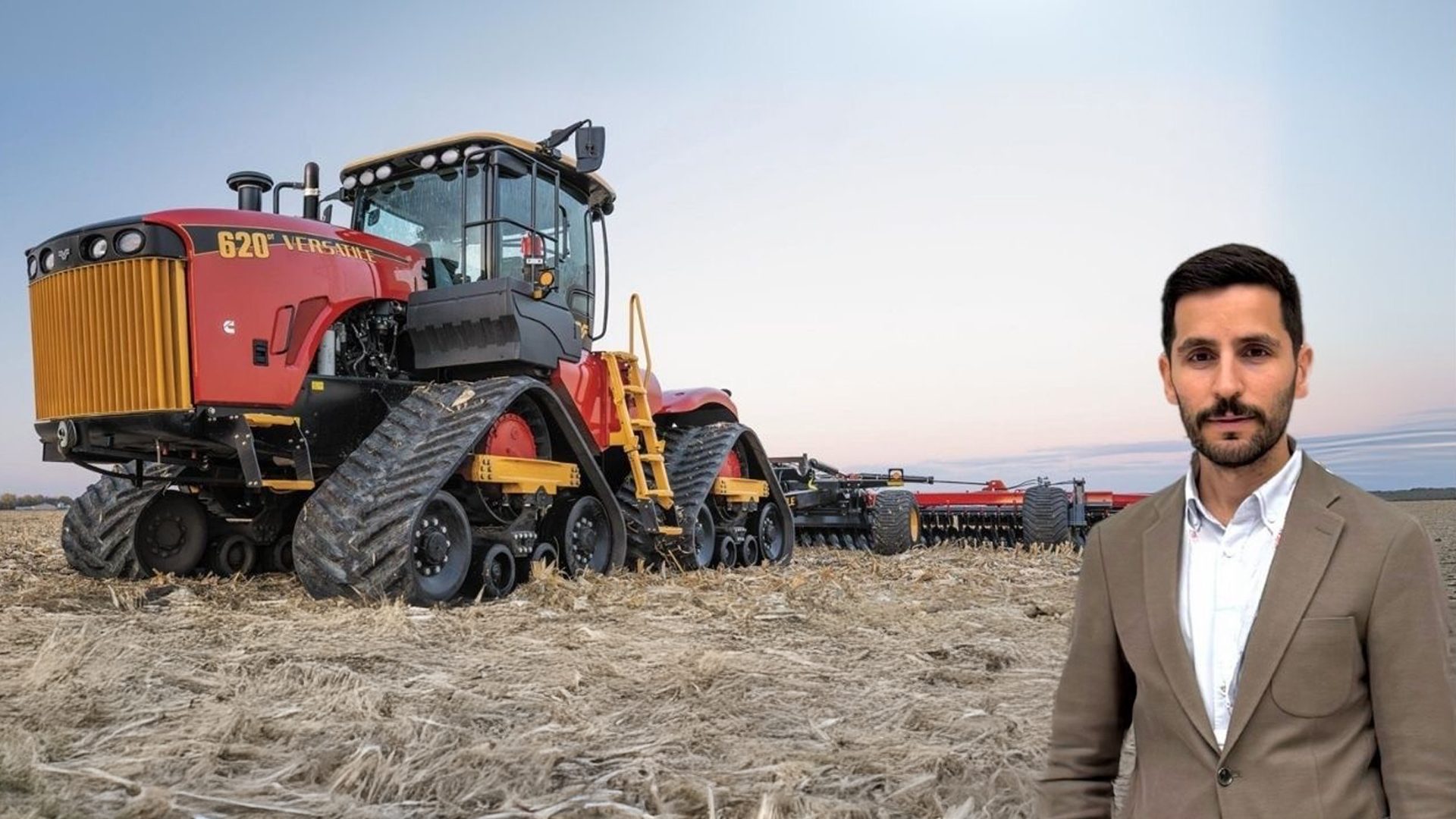 Man next to red Versatile 620 tracked tractor in a field.
