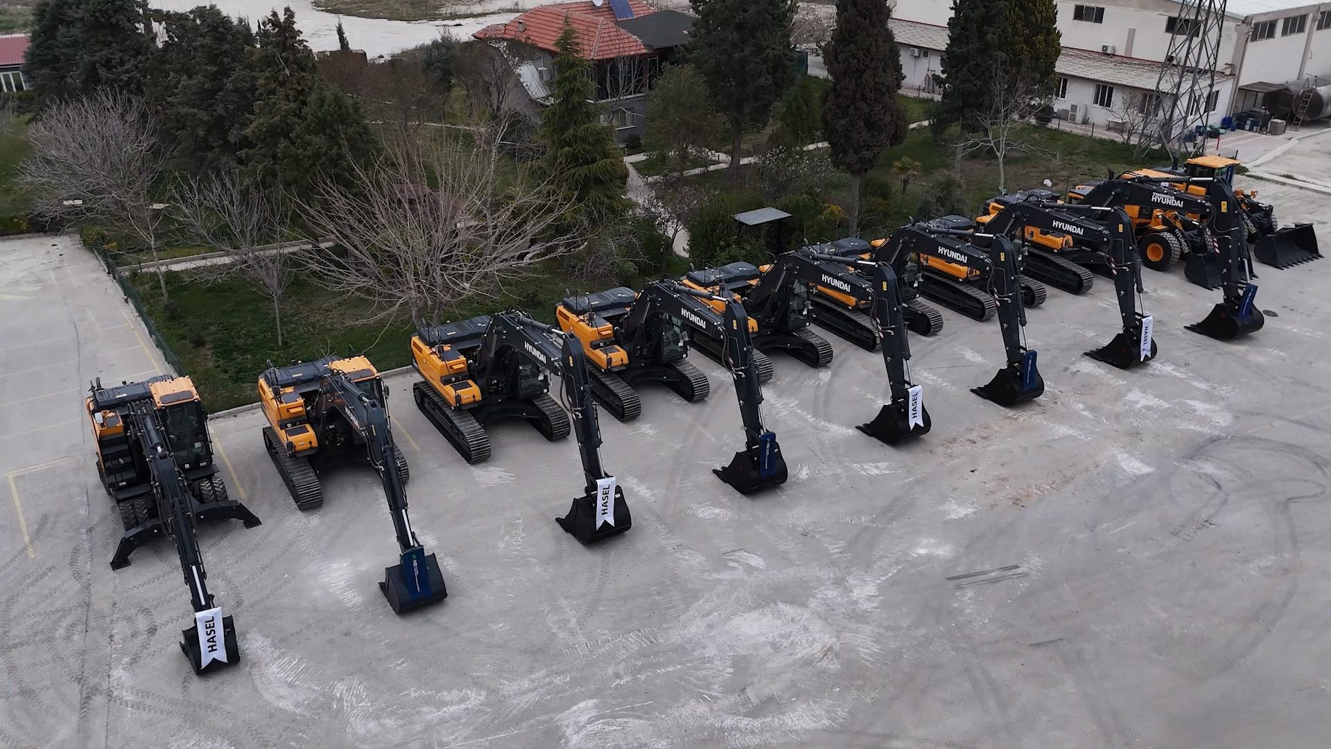 A large fleet of new yellow and black Hyundai excavators and a wheel loader parked outdoors.
