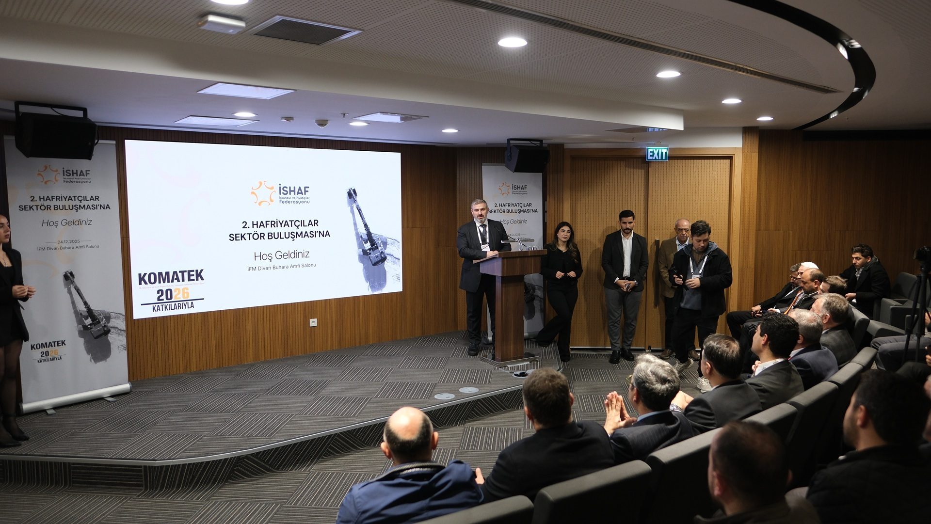 A man presents at the 2nd Excavation Sector Meeting, with İSHAF and KOMATEK 2026 branding.