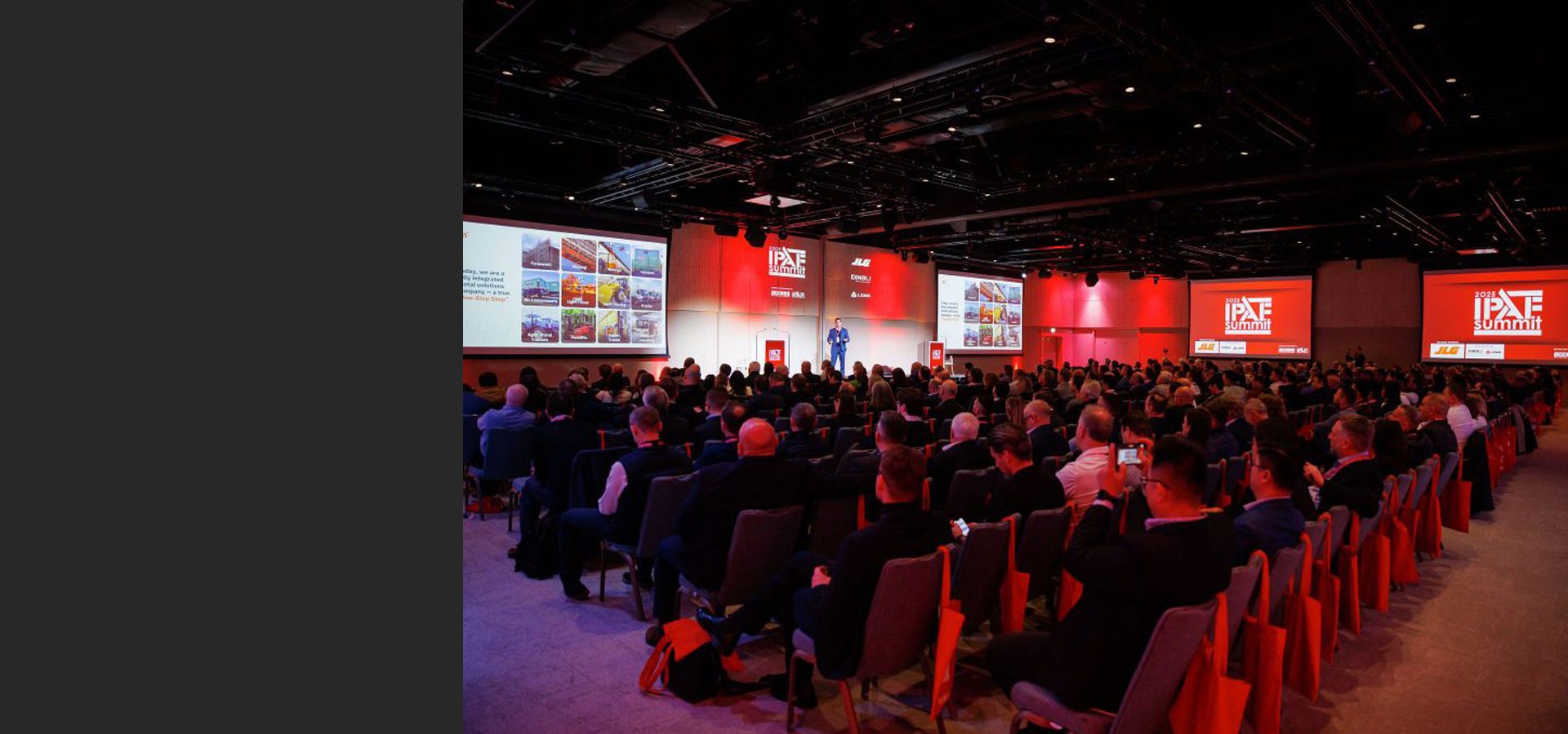 A speaker presents on stage to a large audience at the IPAF Summit, with presentation screens visible.