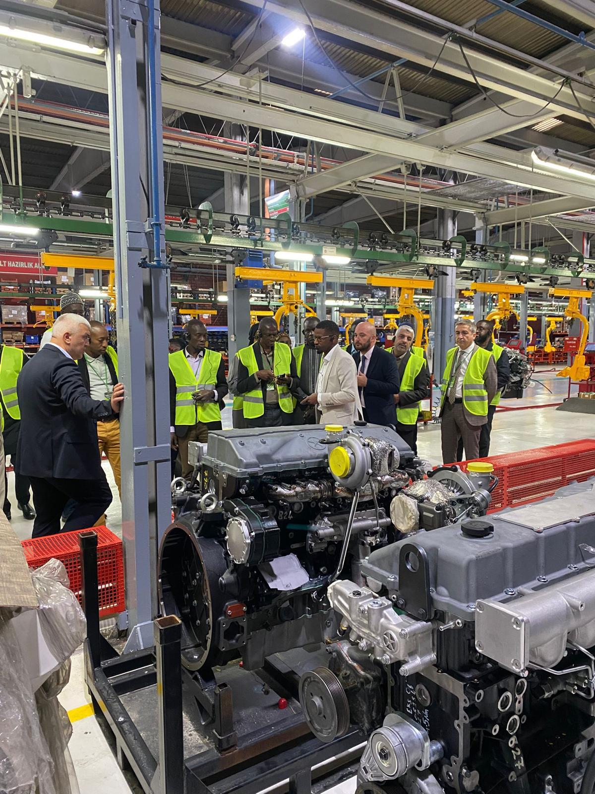 Men in safety vests inspecting large industrial engines in a factory.