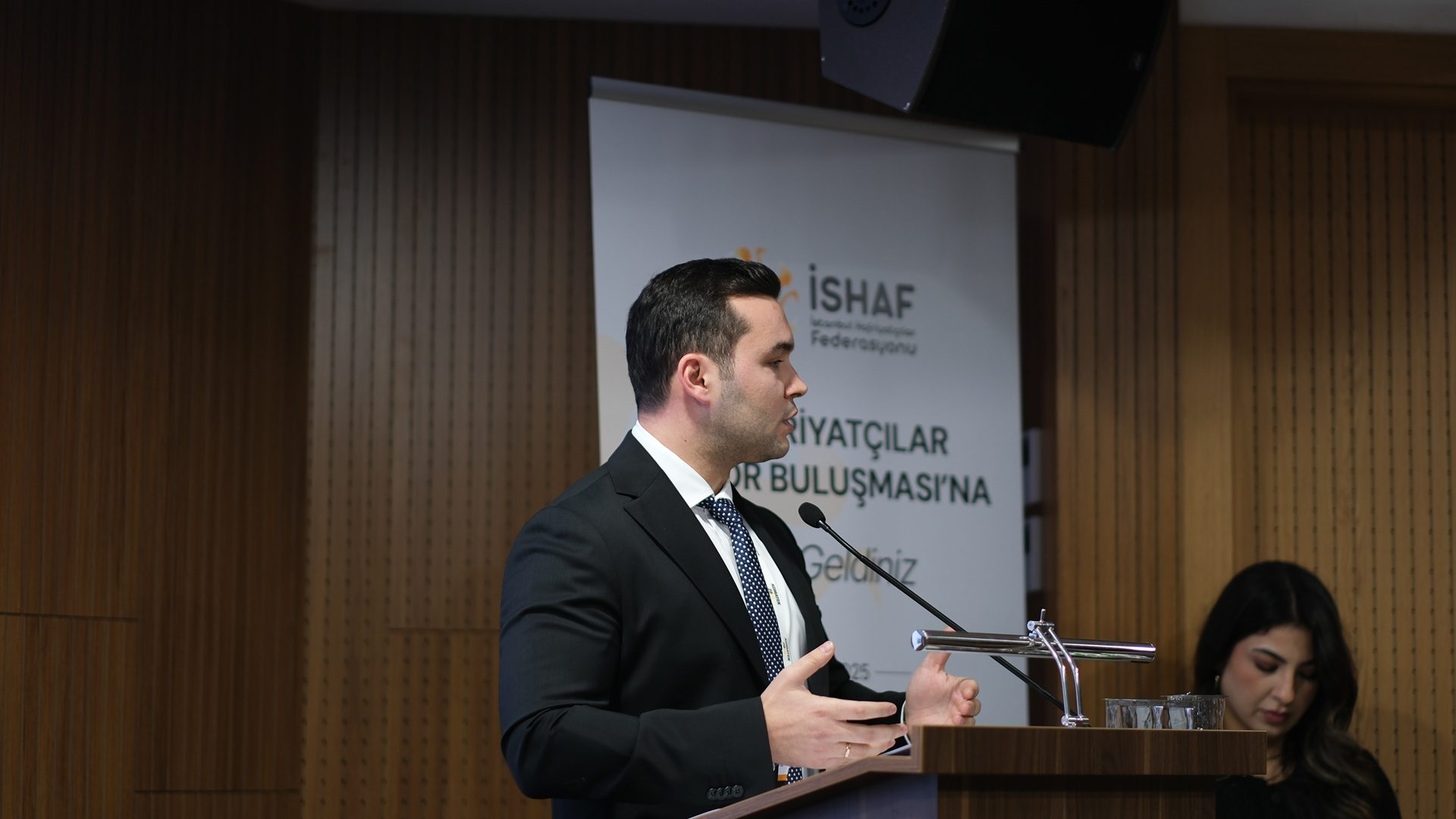 Man in suit speaks at podium at a conference.