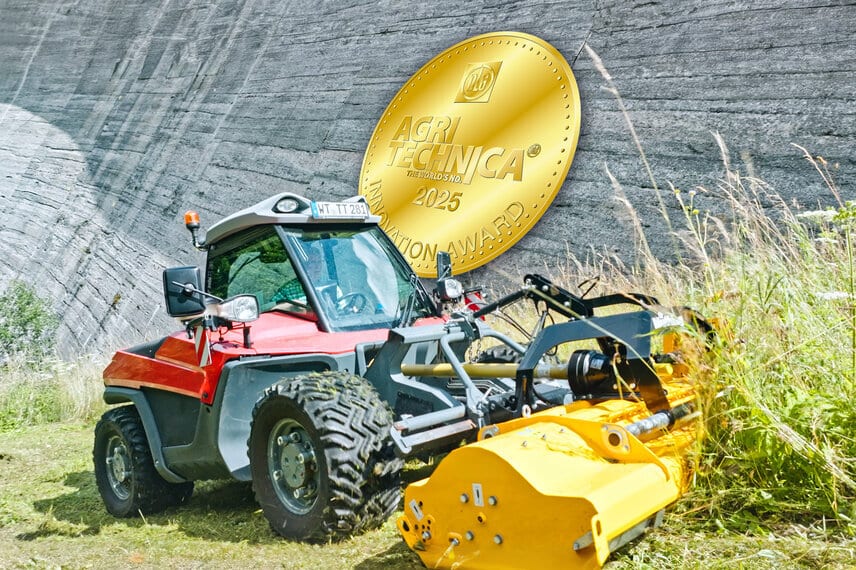 Red farming vehicle with yellow mower against a dam wall, with a golden AGRITECHNICA 2025 Innovation Award.