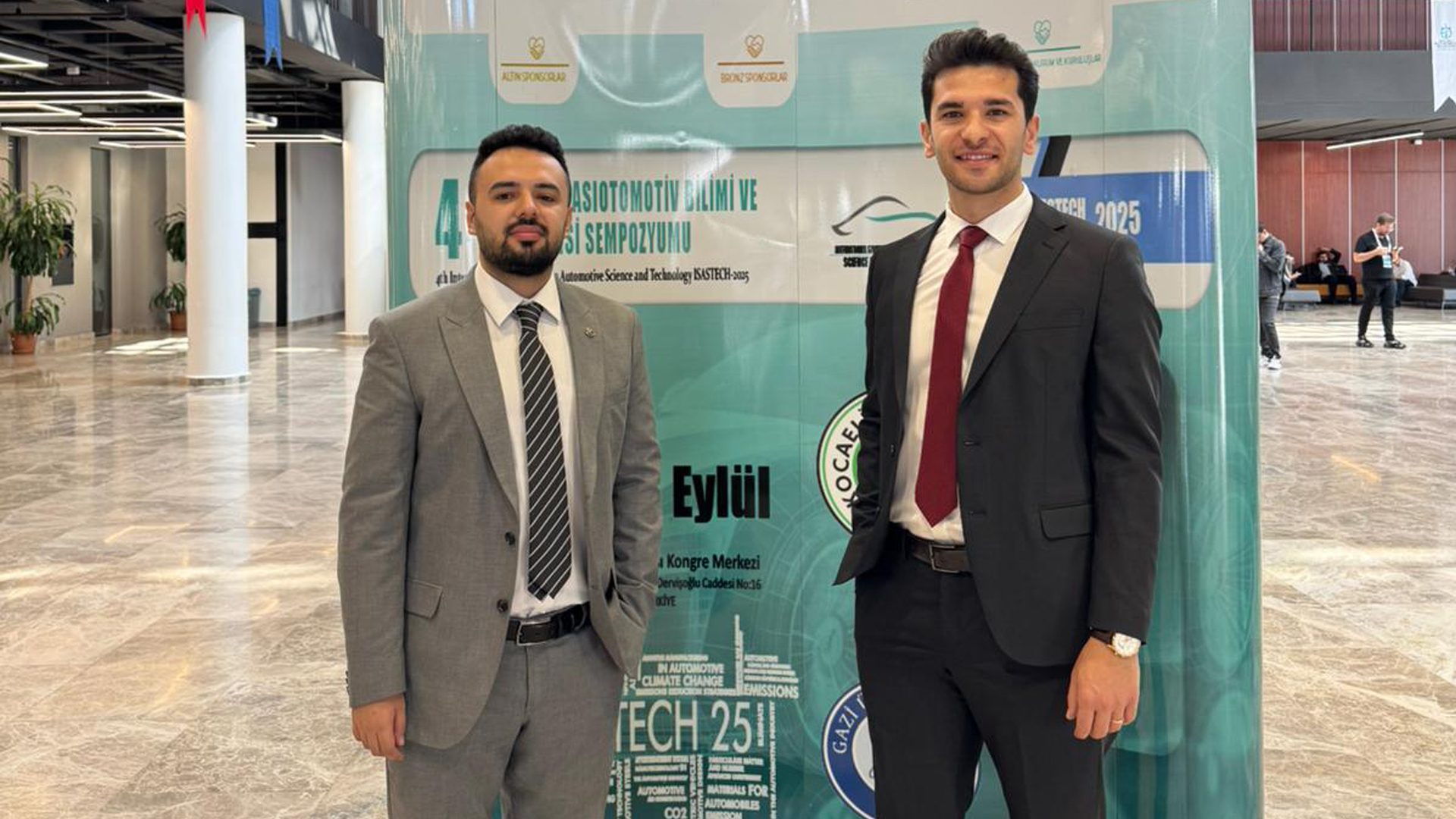Two men in suits smiling at an Automotive Science and Technology event.