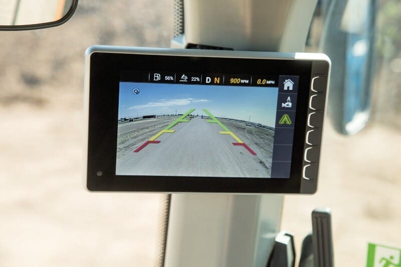 Vehicle display showing a rearview camera feed with guidance lines and vehicle stats.